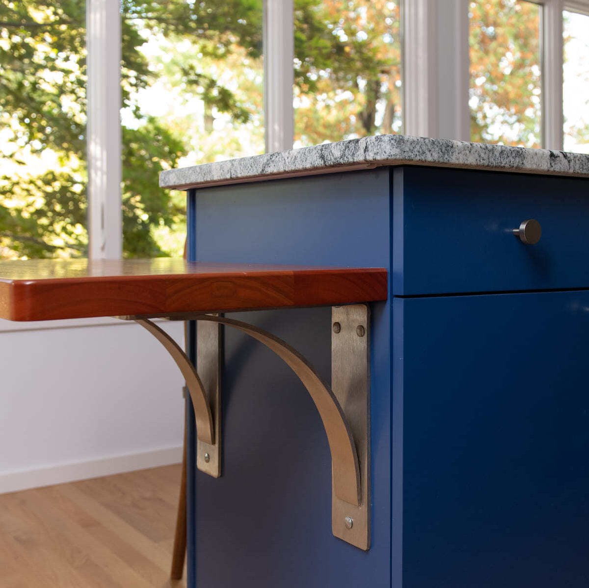 A close-up of a stylish wooden breakfast bar with decorative metal supports in a modern Acton, MA, kitchen