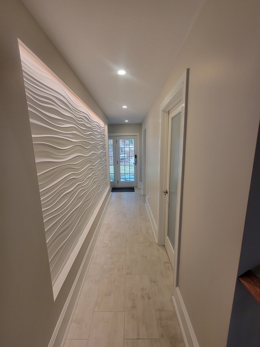 Contemporary corridor featuring a sculptural 3D wall panel, enhancing the minimalist aesthetic of a luxury remodel in Acton, MA