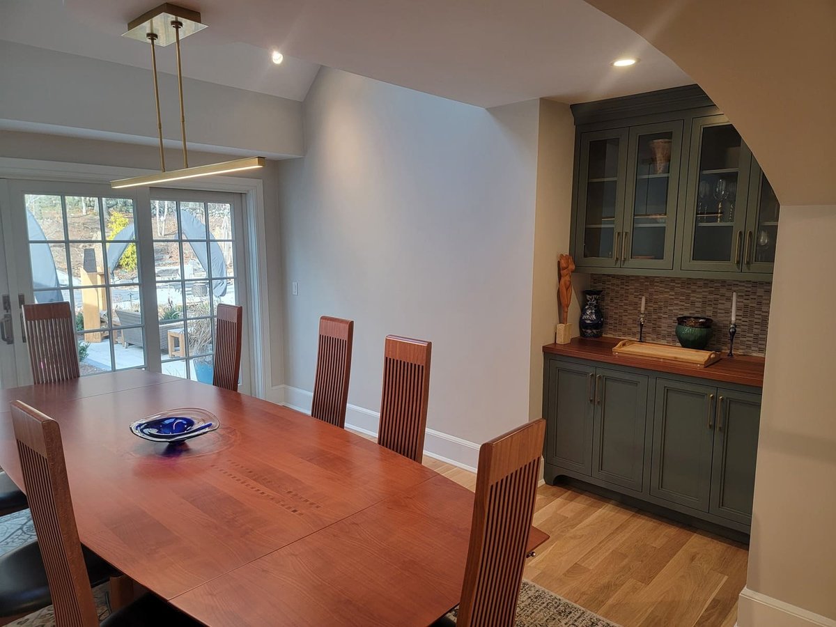Contemporary dining space featuring a minimalist chandelier, elegant built-ins, and large glass doors leading to an outdoor patio