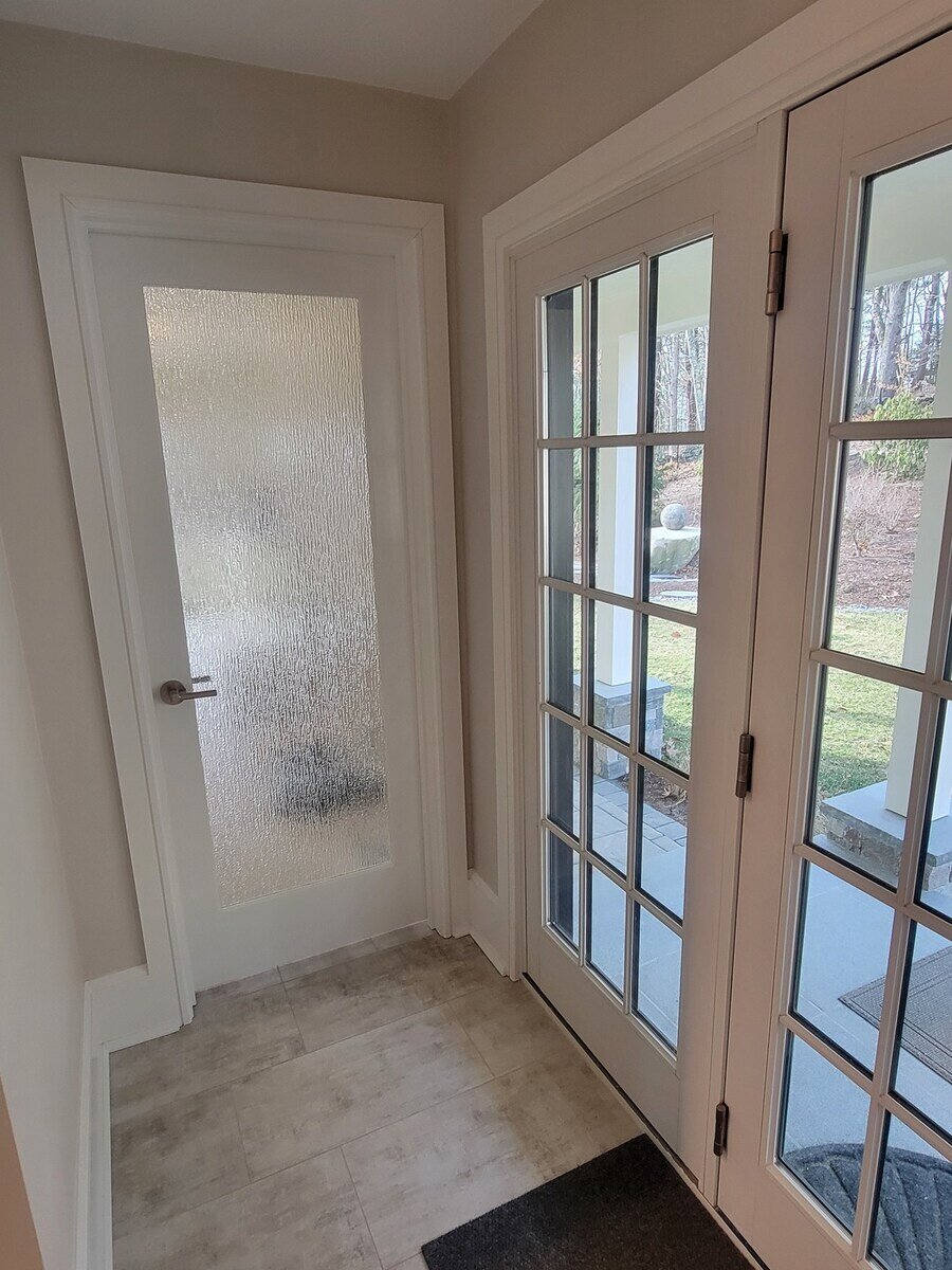 Contemporary mudroom design with a textured privacy door and access to a scenic outdoor area