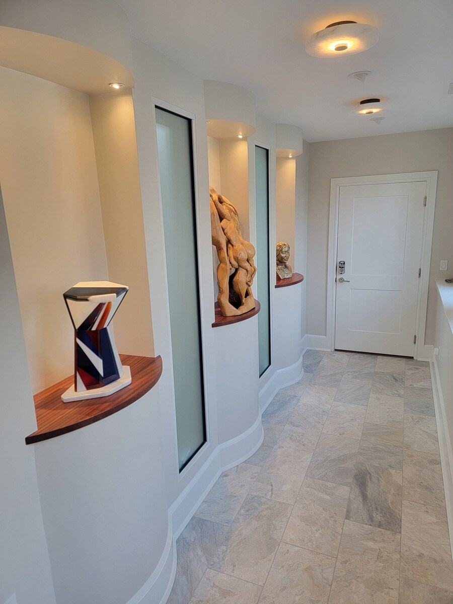 Custom-designed wall niches with accent lighting, featuring sculptural decor in a remodeled space by Thomas Buckborough & Associates