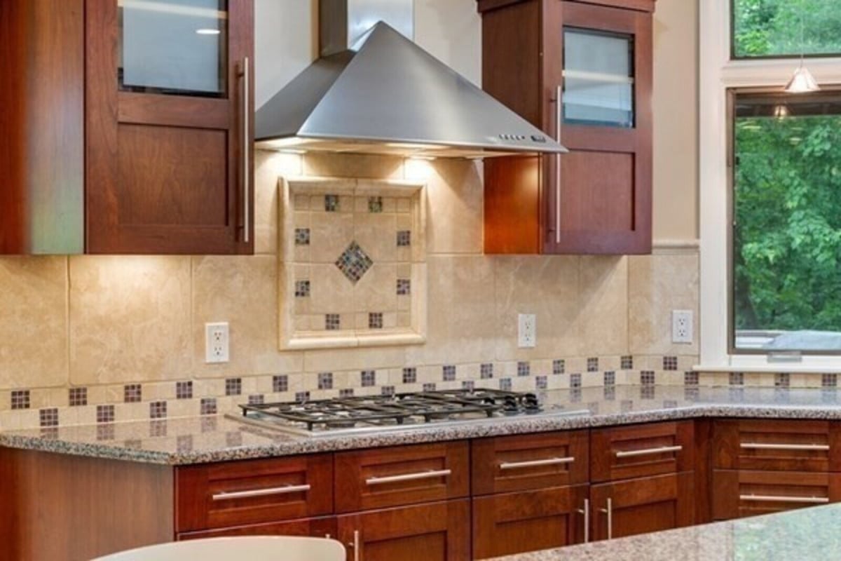 Close-up of stylish kitchen backsplash and modern range hood in Acton, MA remodel by Thomas Buckborough & Associates