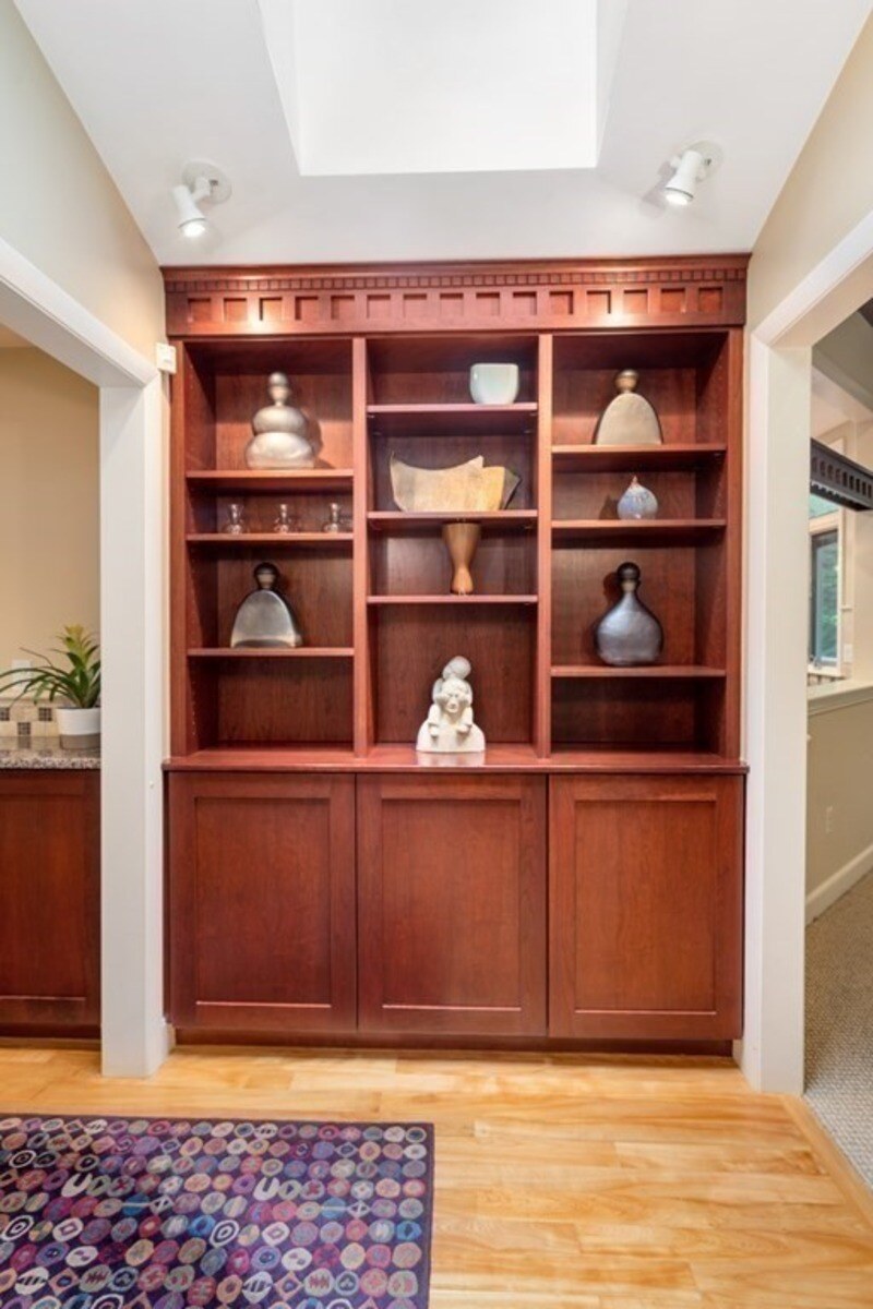 Elegant wooden cabinetry showcasing artistic décor in a custom remodel by Thomas Buckborough & Associates in Acton