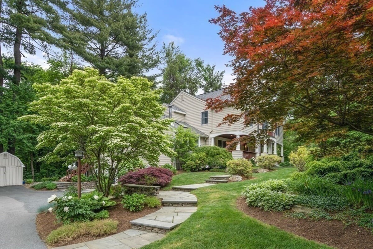 Exterior view of Acton MA home remodel by Thomas Buckborough & Associates with attached garage and lush landscaping