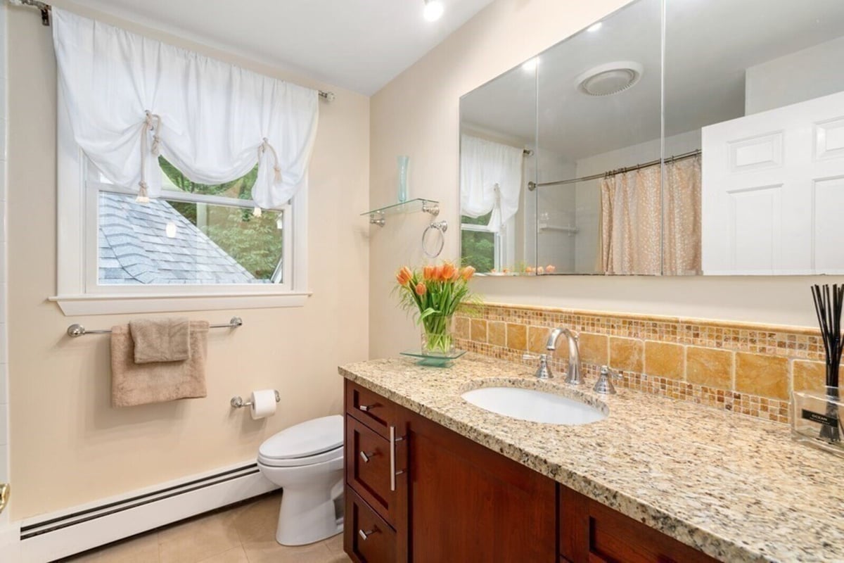 Updated bathroom featuring granite counters and wood cabinetry by Thomas Buckborough & Associates in Acton, MA