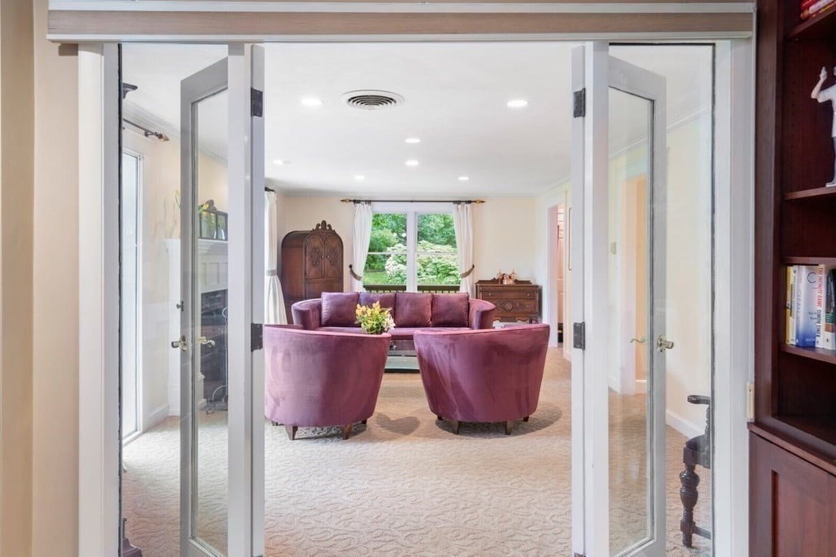 View through glass doors into remodeled living room featuring purple seating, by Thomas Buckborough & Associates in Acton, MA
