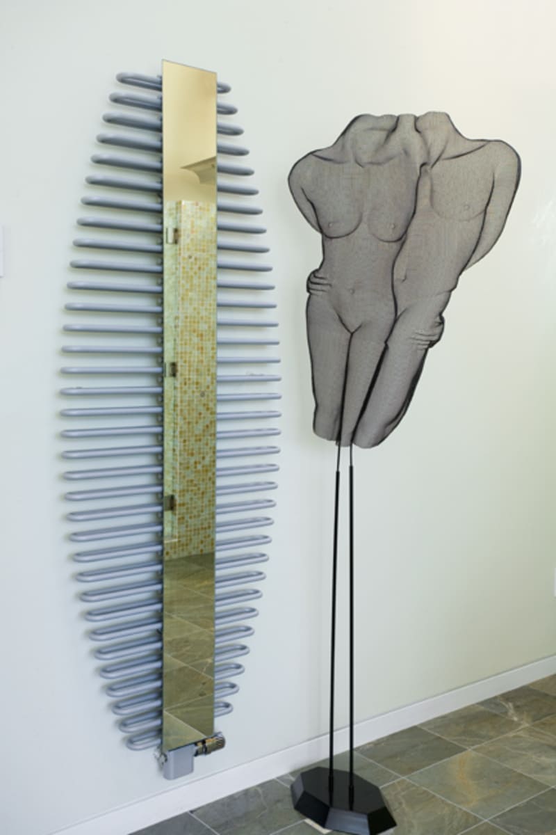 Artistic bathroom corner featuring a sculptural metal artwork and contemporary mirror radiator, designed by Thomas Buckborough & Associates