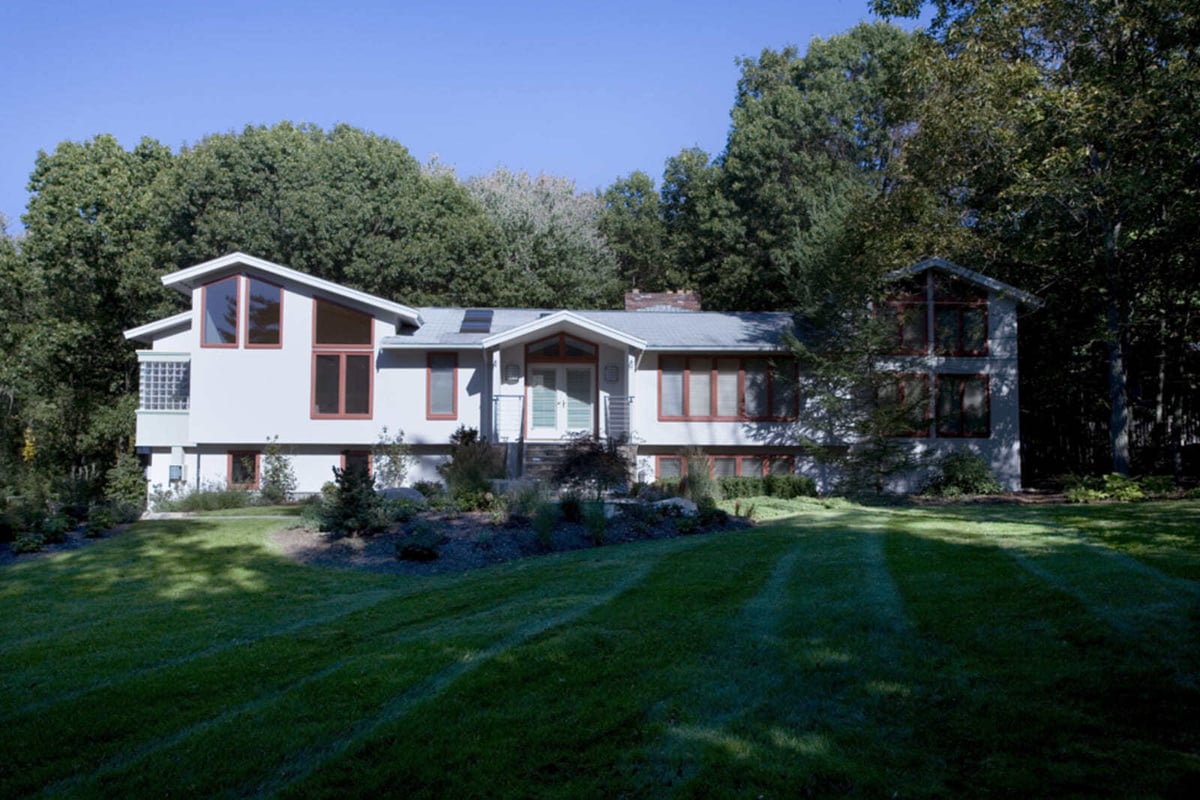 Elegant two-story home with a bright white exterior and natural surroundings in Acton, MA