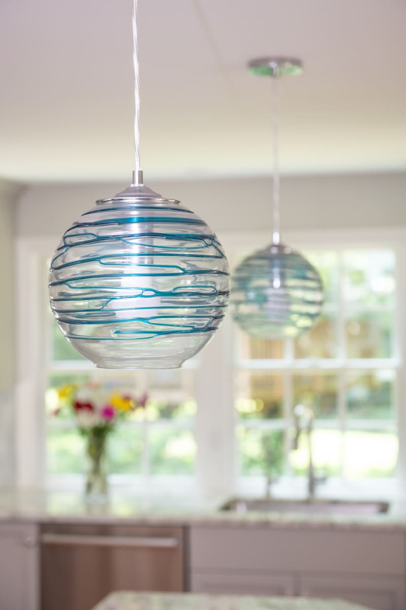A close-up of decorative blue glass pendant lights in a remodeled kitchen by Thomas Buckborough & Associates in Acton, MA