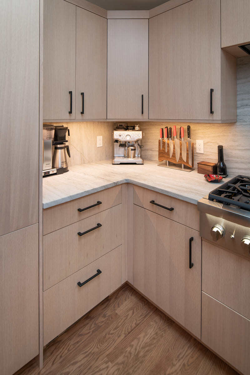 Elegant corner kitchen with built-in storage and under-cabinet lighting in a Shea home remodel by Thomas Buckborough & Associates in Acton, MA