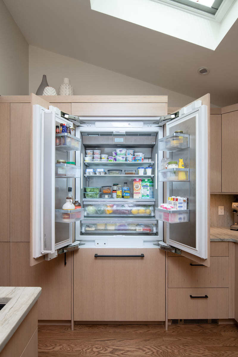 Fully stocked refrigerator with bright interior lighting and efficient organization in a contemporary kitchen design
