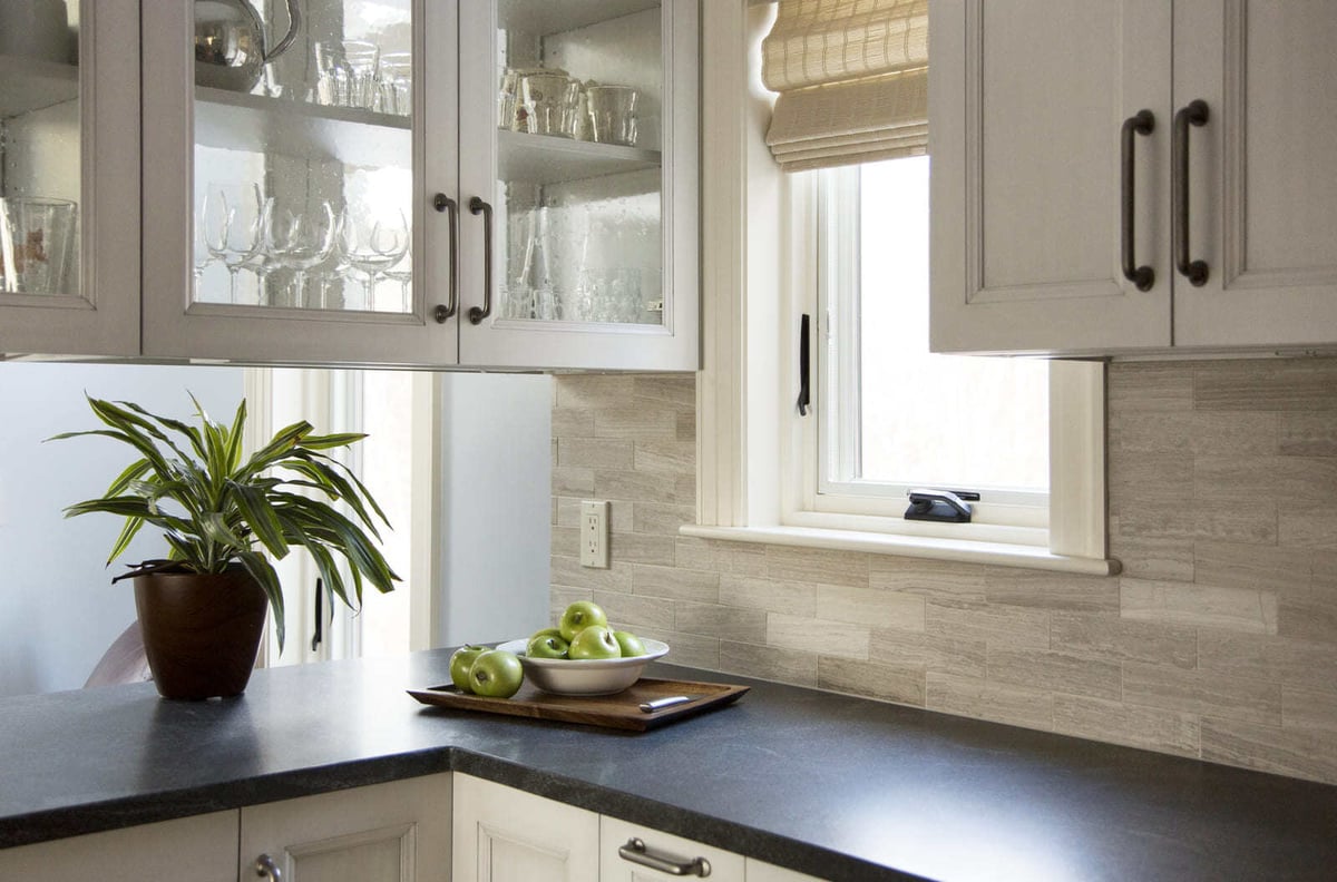 Stylish kitchen featuring black stone countertops, a large central island, and decorative glass-front cabinetry by Thomas Buckborough & Associates, Acton, MA