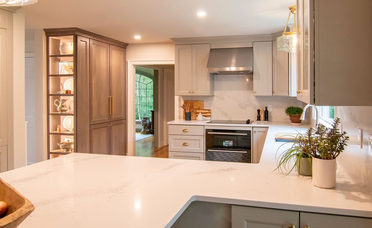 Modern gray kitchen with shaker cabinets, white quartz countertops, and a large island, opening into a bright living room. (1)