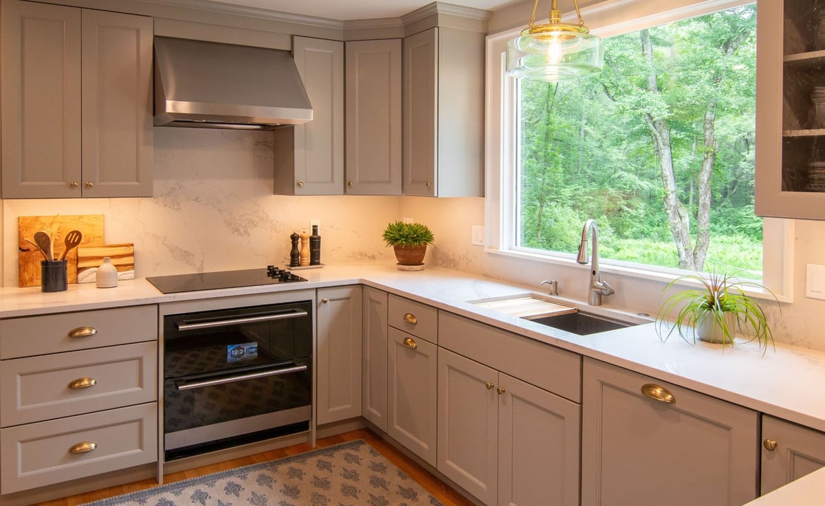 Modern gray kitchen with shaker cabinets, white quartz countertops, and a large island, opening into a bright living room. (10)
