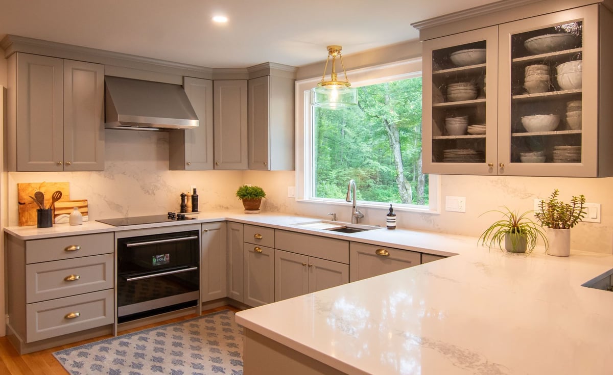 Modern gray kitchen with shaker cabinets, white quartz countertops, and a large island, opening into a bright living room. (3)