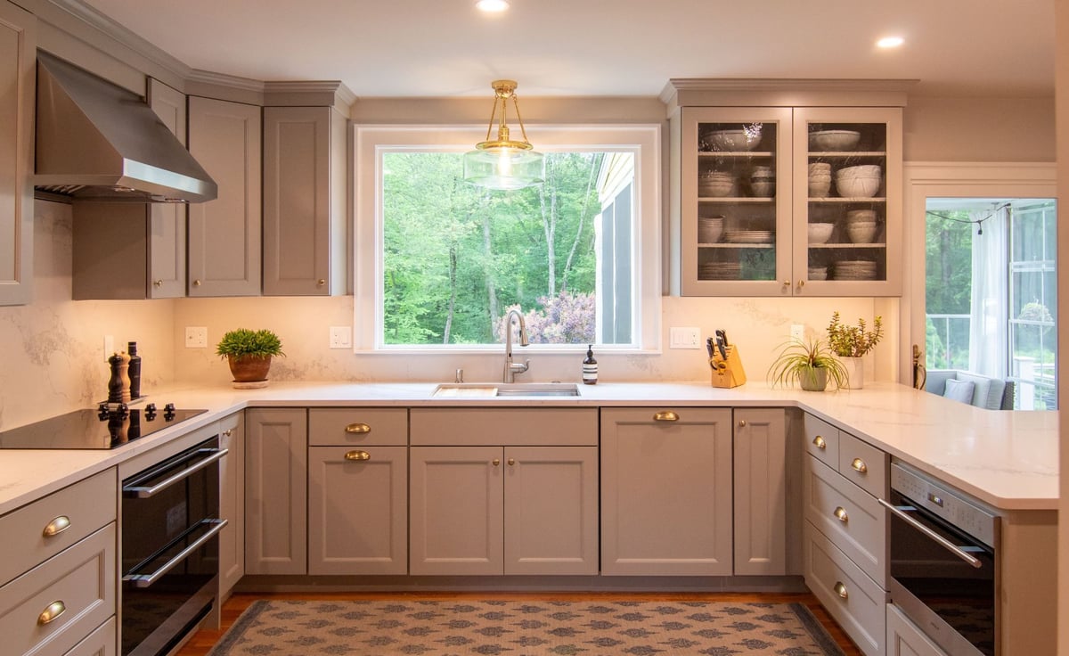 Modern gray kitchen with shaker cabinets, white quartz countertops, and a large island, opening into a bright living room. (4)