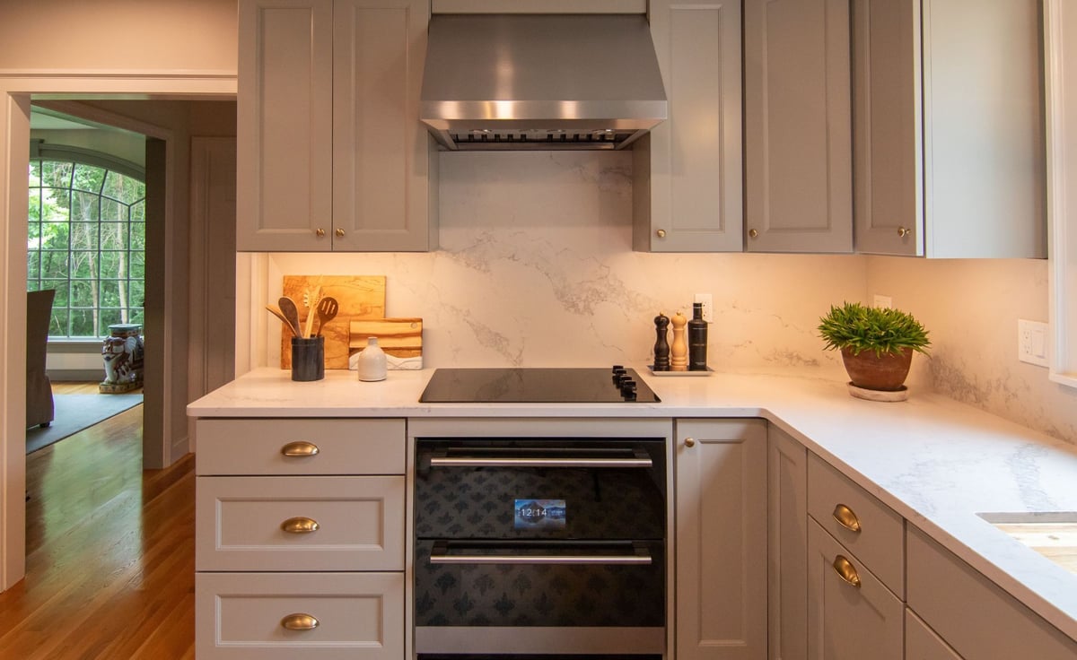 Modern gray kitchen with shaker cabinets, white quartz countertops, and a large island, opening into a bright living room. (7)