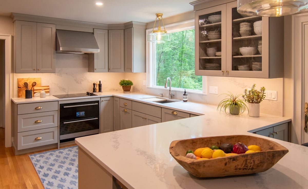 Modern gray kitchen with shaker cabinets, white quartz countertops, and a large island, opening into a bright living room. (9)